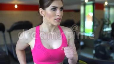 运动迷人的白种人年轻女子在健身房做有氧运动。 健身女孩，穿粉色上衣的女运动员